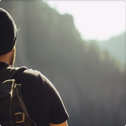 man from behind, wearing a beanie and looking at a mountainrange