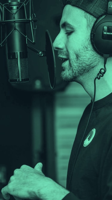 man with headphones speaking to a microphone, recording a podcast